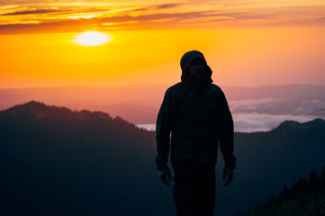 Man Traveler silhouette walking alone outdoor with sunset mountains on background Travel Lifestyle and survival concept