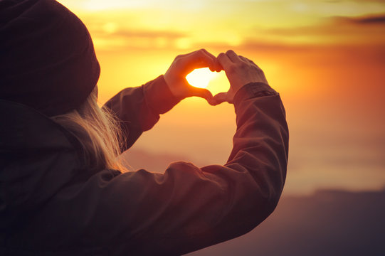Woman hands Heart symbol shaped Travel Lifestyle and Feelings concept with sunset sky nature on background