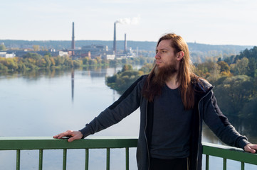 Portrait of man with a long beard and a long hair near the river