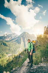 Young Man Traveler with backpack relaxing outdoor with rocky mountains on background Summer vacations and Lifestyle hiking concept