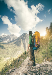 Young Man with backpack relaxing outdoor Travel Lifestyle hiking concept with rocky mountains on background Summer vacations