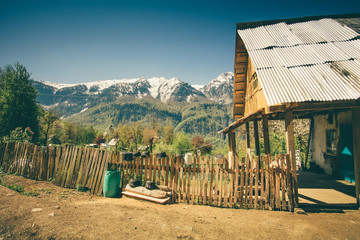 Highland village traditional wooden house and fence with Mountains Landscape snowy peaks on background beautiful scenery in Abkhazia
