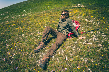 Naklejka na ściany i meble Man Traveler with backpack relaxing on valley grass outdoor Travel Lifestyle concept Summer vacations