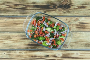 Vegetable salad in a glass dish on wooden background