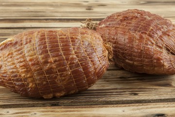 Smoked boneless pork ham hock wrapped in netting on a wooden background