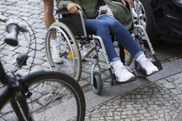 closeup of woman in wheelchair at steps of sidewalk