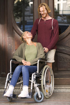 woman in wheelchair in front of entrance with friend