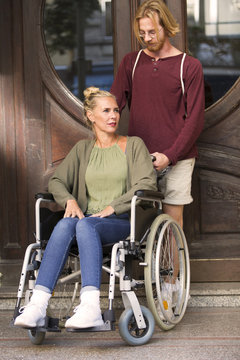 woman in wheelchair at an entrance with young man