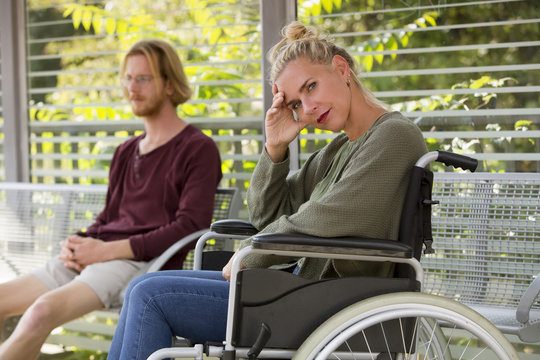 woman in wheelchair and young man sitting on bench