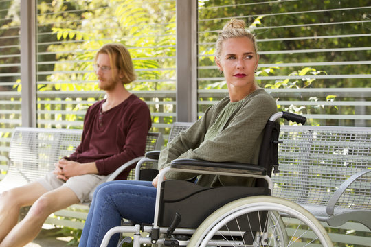 woman in wheelchair next to young man on bench