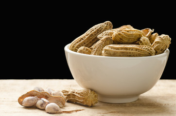 Boiled peanuts in a bowl and peeled peanuts on wooden ready to eating