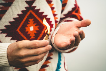 Man hands holding fire burning match Travel Lifestyle survival concept wearing knitted sweater outdoor