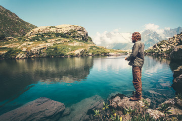 Naklejka premium Man Fisherman fishing with rod lake and mountains on background Lifestyle Travel hobby concept active summer vacations