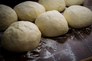Fototapeta na wymiar Dough balls on wooden table with flour