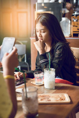 soft focus and grain added in warm tone. Photo of girl playing smart phone in a cafe . Represent about lifestyle of teenage.