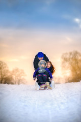 family rides the sledge in the wood