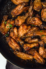 Teriyaki chicken wings in skillet. Top view, vertical.