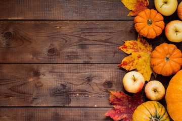 Pumpkins, autumn fallen leaves and apples on wooden background. Fall, Thanksgiving concept