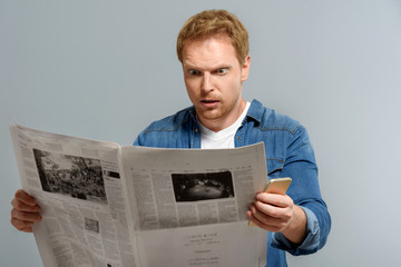 upset guy holding newspaper on gray background