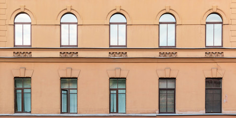 Several windows in a row on facade of urban apartment building front view, St. Petersburg, Russia.