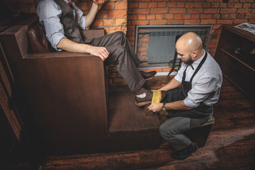 bearded craftsman cleaning footwear of a man