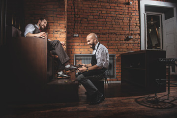 guy having a drink while worker shining shoes