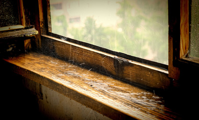 Raindrops breaking on old wooden window sill. Vintage stylization