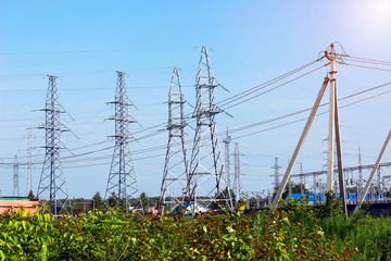 High-voltage electric poles near a power substation on blue sky background