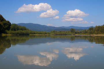 Clouds are reflected on a mountain river in summer
