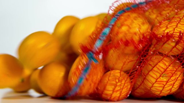 Close-up of falling sack and  clementines that are getting out of it. On white background. Slow motion