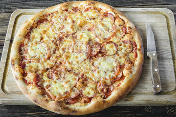 Pizza on the cutting board and knife beside