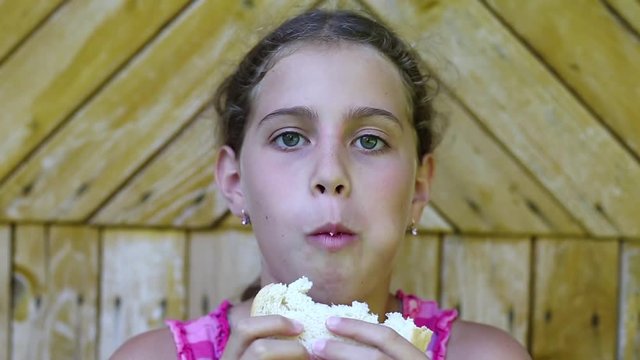 Pretty girl eats slice of white bread. Girl eats bread