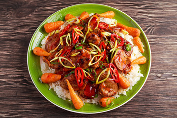 takeawy classic pork on rice with fried in sticky souce carrots, sprinkle of chillie and spring onion.