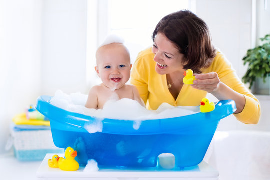 Happy Baby Taking A Bath Playing With Foam Bubbles. Mother Washing Little Boy. Young Child In A Bathtub. Smiling Kids In Bathroom With Toy Duck. Mom Bathing Infant. Parent And Kid Play With Water.