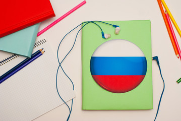 the book with russian flag and blue hearphones. concept of russian learning through audio courses