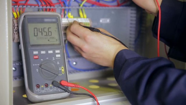 Electrician testing electrical power. Industrial factory electrician testing voltage using voltmeter at the electrical shield. HD.