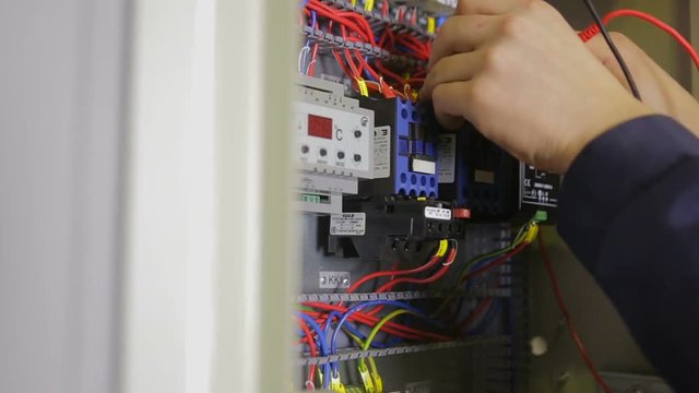 Electrician testing electrical power. Industrial factory electrician testing voltage using voltmeter at the electrical shield. HD.