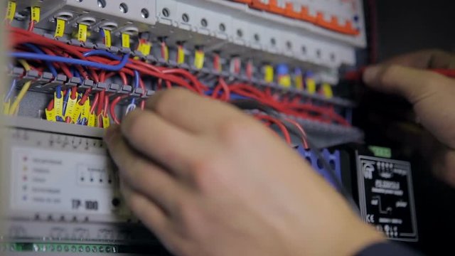 Electrician testing electrical power. Industrial factory electrician testing voltage using voltmeter at the electrical shield. HD.