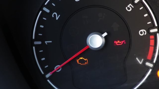 Color footage with various icons lighting up on a car's dashboard, with engine starting and stopping.
