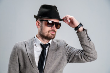 bearded man in strict classical style in a black hat holds it wi