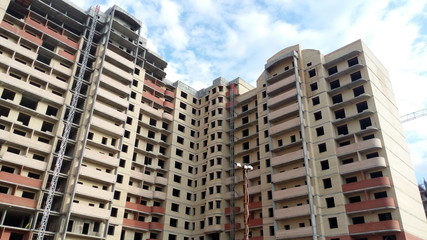 Fototapeta premium Under construction high-rise brick building on blue sky background