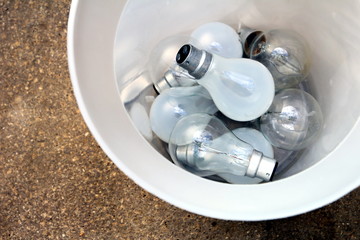 Inefficient tungsten light bulbs discarded in a trash can - green eco concept