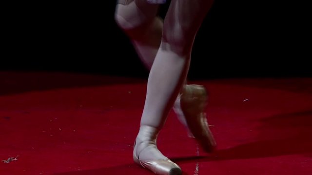 Ballerina in pointe dancing on a red circus.