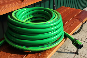 Garden hose bundle on the bench in the summer garden