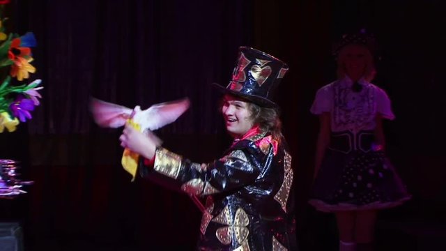 magician performs the trick with white a pigeon