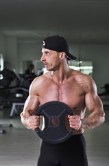 Handsome powerful athletic man performing static exercise with weight. Strong bodybuilder with ...
