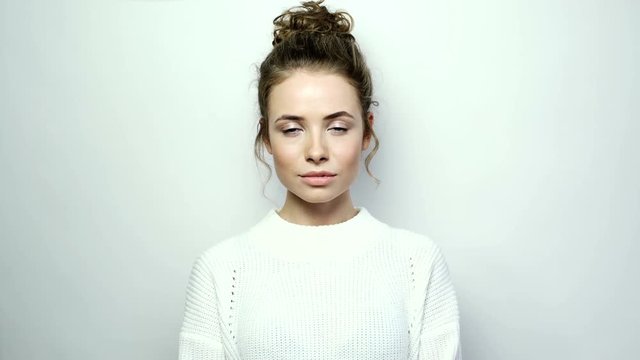 Front portrait of the beautiful smiling woman looking at camera over white background.