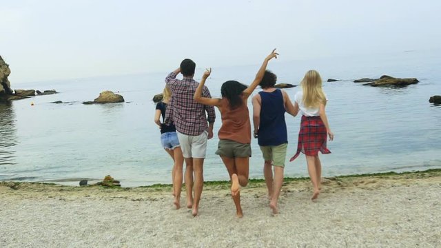Five friends running on the beach.