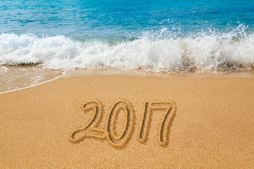 Drawing in sand by ocean of 2017 word