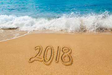 Drawing in sand by ocean of 2018 word